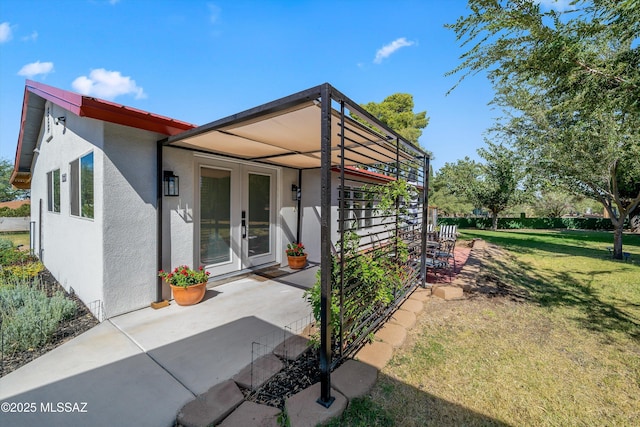 exterior space featuring a patio area, french doors, a lawn, and stucco siding