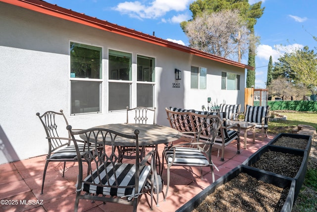 rear view of property featuring a patio, outdoor dining space, and stucco siding