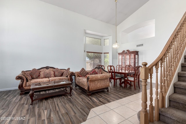 living room featuring baseboards, visible vents, wood finished floors, stairway, and high vaulted ceiling