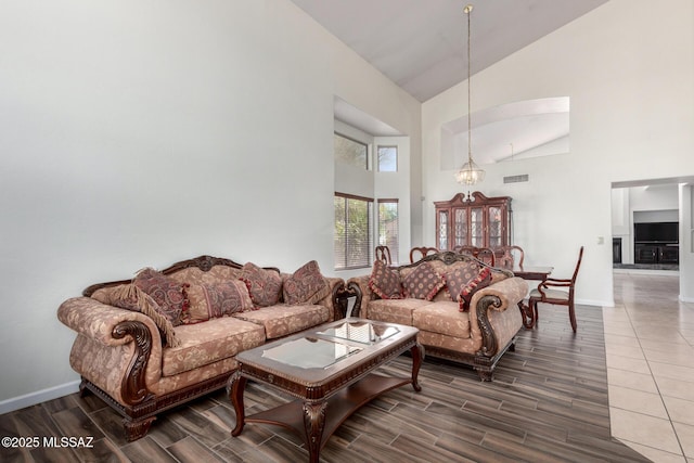 living room with baseboards, wood finish floors, visible vents, and high vaulted ceiling
