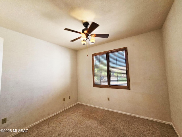 carpeted spare room featuring baseboards and ceiling fan