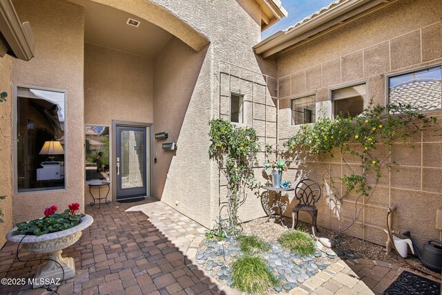 doorway to property featuring a patio, visible vents, and stucco siding