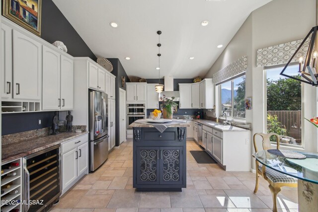 kitchen featuring appliances with stainless steel finishes, white cabinets, a sink, a center island, and wine cooler