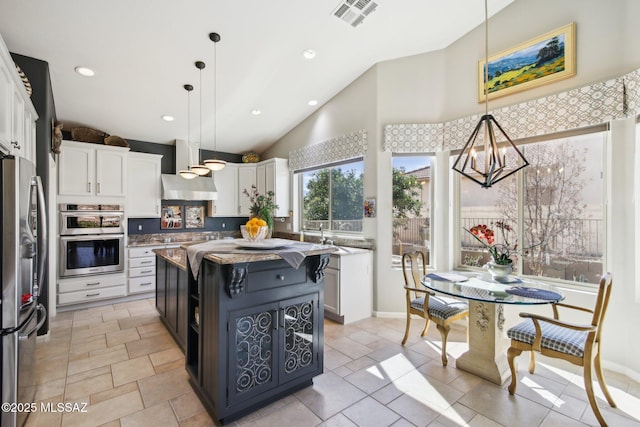 kitchen with an inviting chandelier, light stone counters, appliances with stainless steel finishes, white cabinets, and visible vents