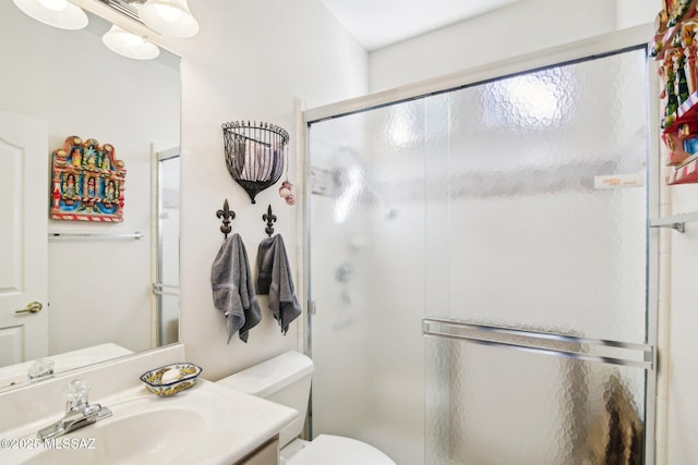 bathroom with toilet, vanity, and a shower stall