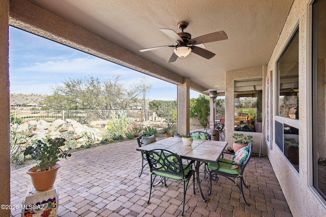 view of patio with a ceiling fan, outdoor dining space, and fence