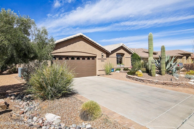 single story home with stucco siding, concrete driveway, a tile roof, and a garage
