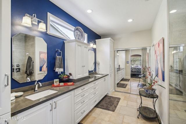 full bathroom with double vanity, plenty of natural light, ensuite bathroom, and a sink