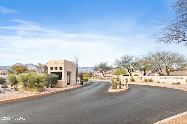 view of street with a gated entry, a gate, curbs, and a mountain view