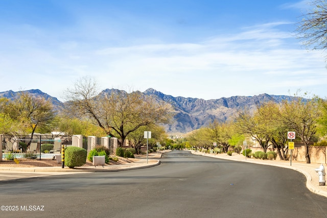 view of street with a mountain view, traffic signs, and curbs