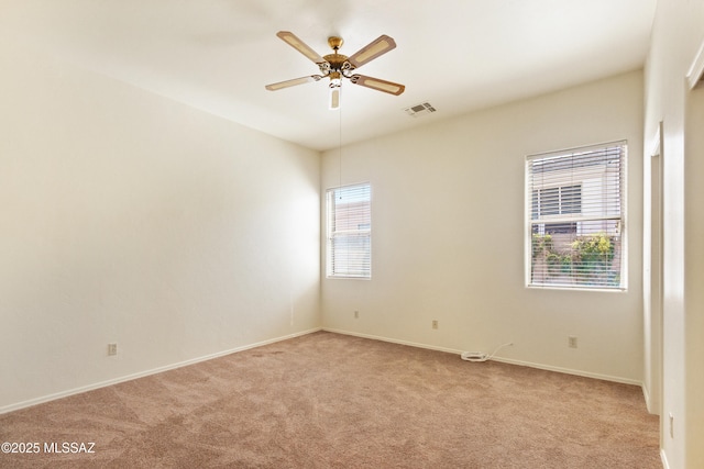 empty room featuring light colored carpet, visible vents, ceiling fan, and baseboards