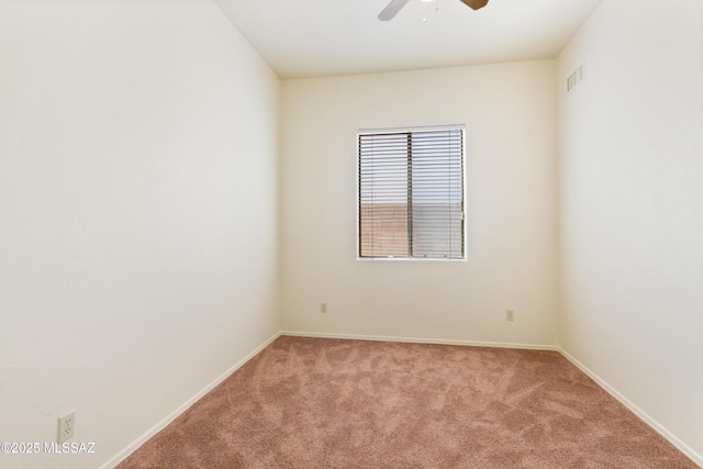 carpeted empty room with baseboards, visible vents, and a ceiling fan