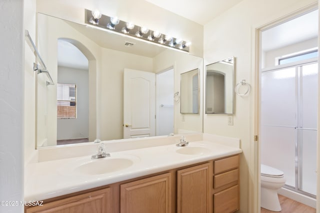 full bathroom with double vanity, a sink, toilet, and a shower stall