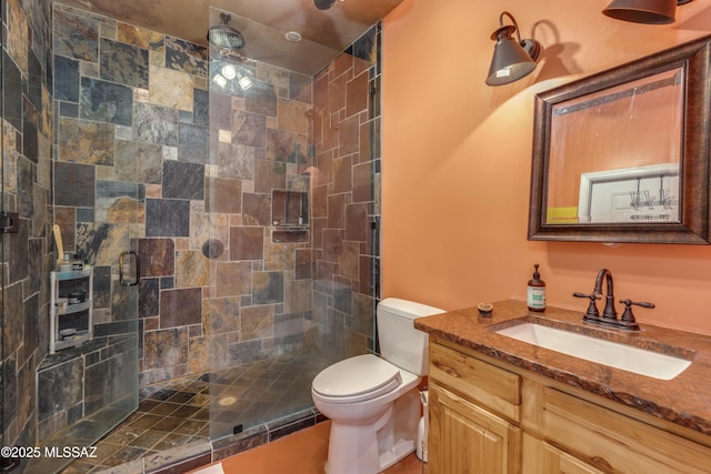full bath with a stall shower, toilet, and vanity