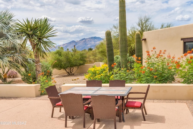 view of patio featuring outdoor dining area, a mountain view, and fence