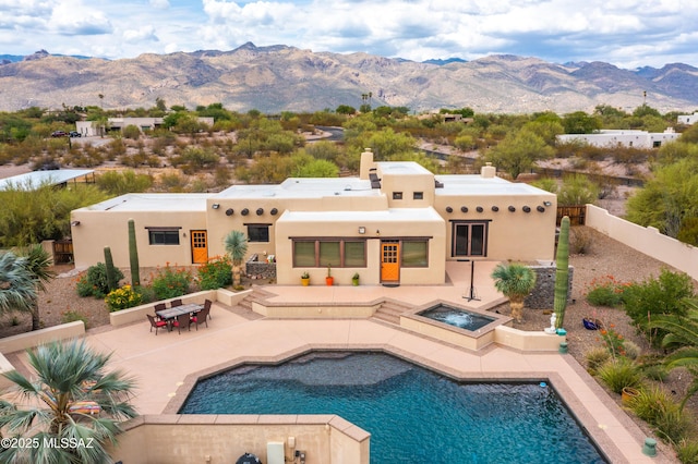 back of property with an in ground hot tub, a fenced backyard, a patio, an outdoor pool, and a mountain view