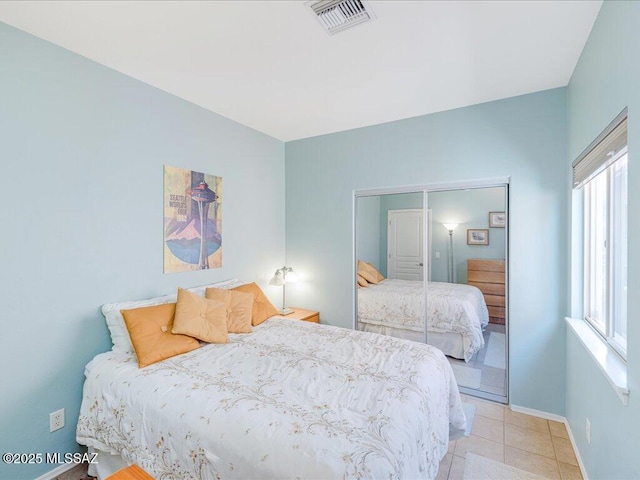 bedroom with light tile patterned floors, visible vents, a closet, and baseboards