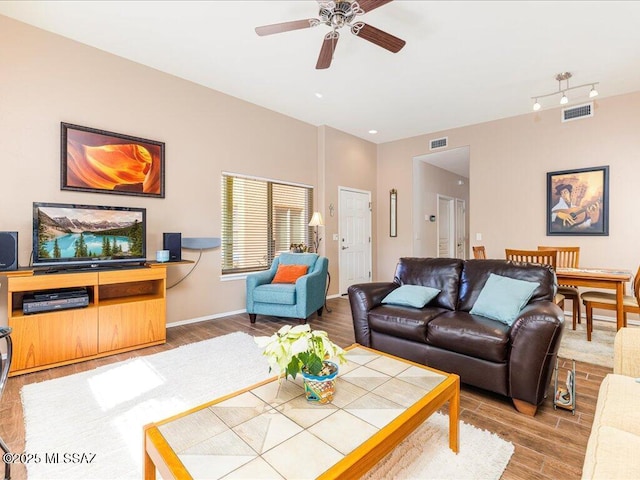 living area featuring baseboards, visible vents, wood finished floors, and ceiling fan