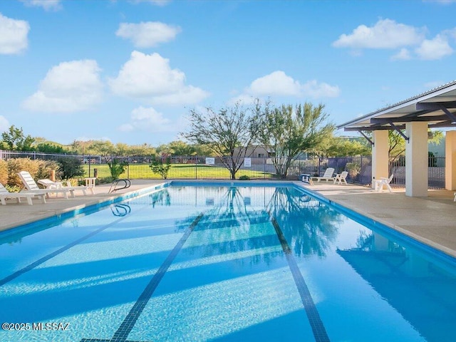 community pool with a patio area and fence