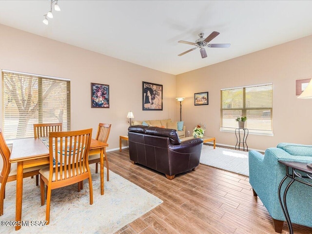 living area featuring a ceiling fan, light wood finished floors, and baseboards