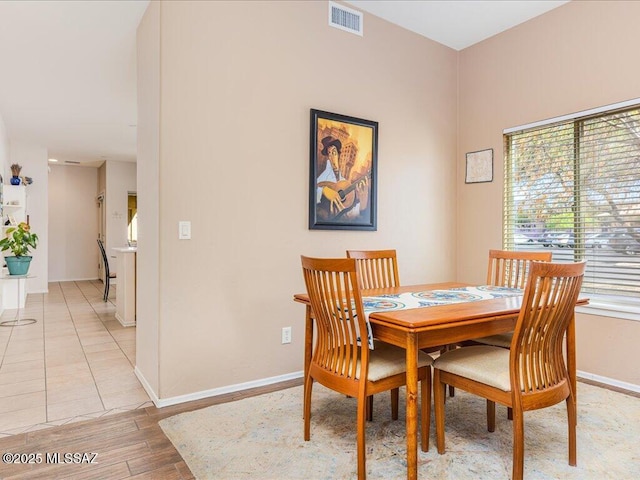 dining space with light wood-type flooring, visible vents, and baseboards