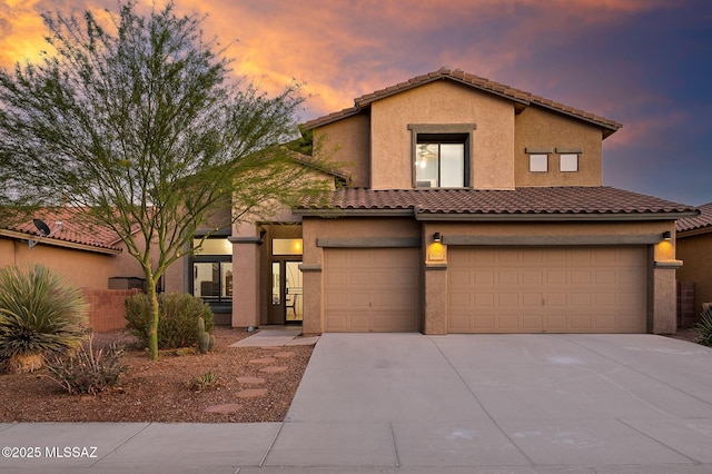 view of front of property featuring driveway, a tiled roof, stucco siding, and a garage