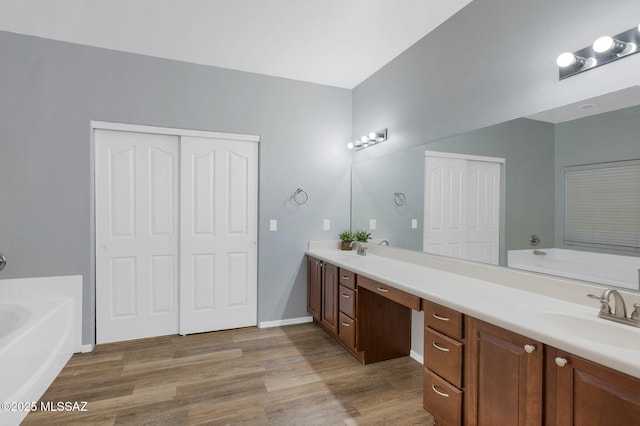 full bath with a garden tub, double vanity, and a sink