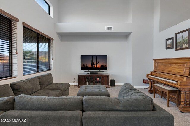 carpeted living area featuring a towering ceiling, visible vents, and baseboards
