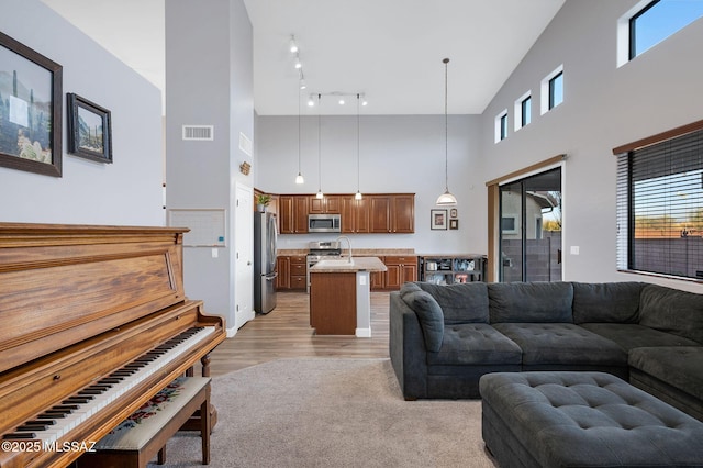 living room with light wood-style flooring, visible vents, and high vaulted ceiling