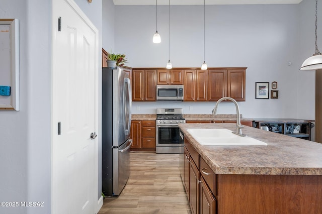 kitchen featuring brown cabinets, appliances with stainless steel finishes, light wood-style flooring, and a sink