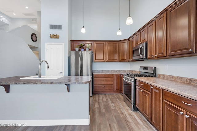 kitchen with a breakfast bar, a high ceiling, visible vents, and stainless steel appliances