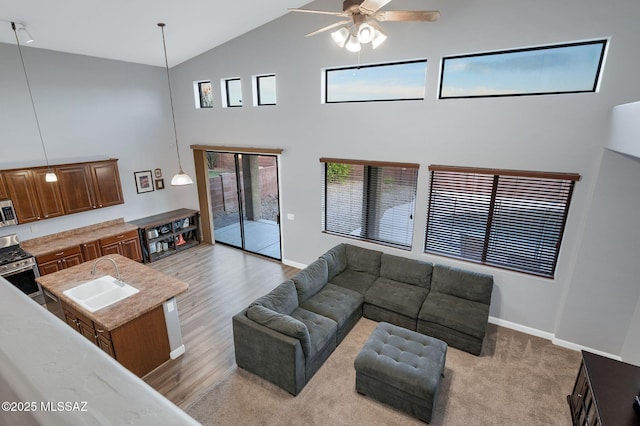 living room featuring high vaulted ceiling, ceiling fan, and baseboards