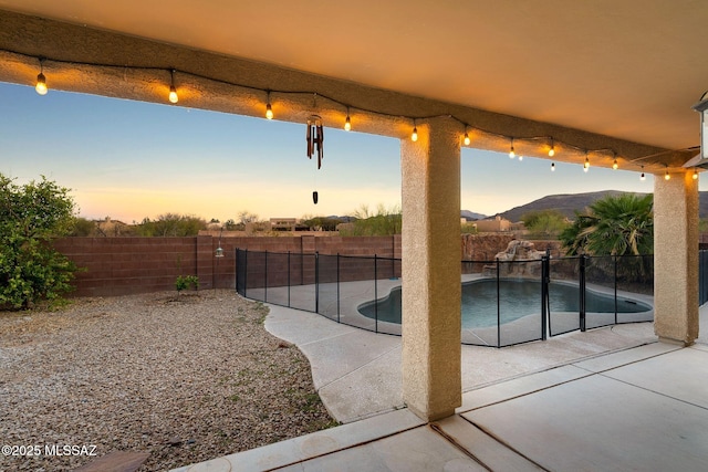 pool at dusk featuring a fenced in pool, a patio, and a fenced backyard