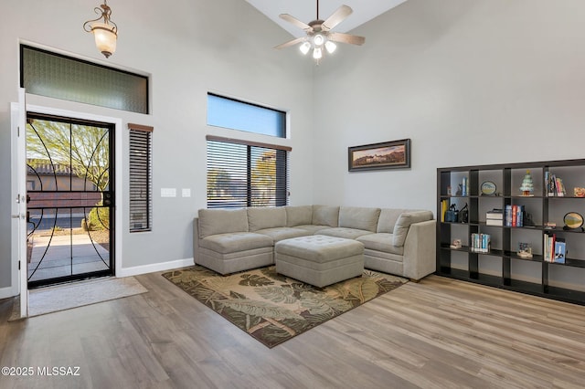 living room with high vaulted ceiling, wood finished floors, ceiling fan, and plenty of natural light