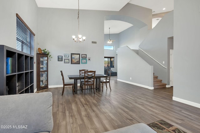 dining room with stairway, wood finished floors, a high ceiling, and plenty of natural light