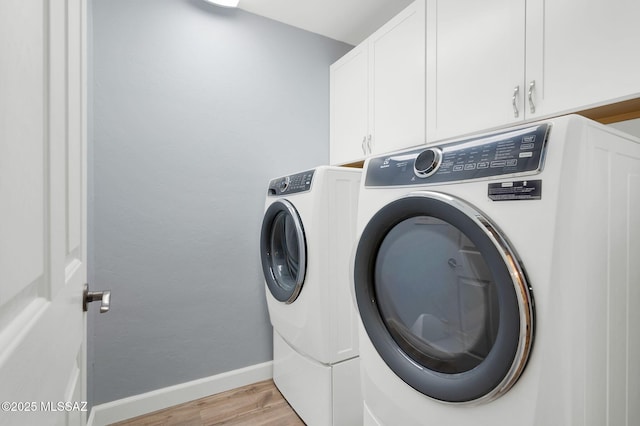 laundry area with cabinet space, baseboards, light wood-style flooring, and washer and clothes dryer