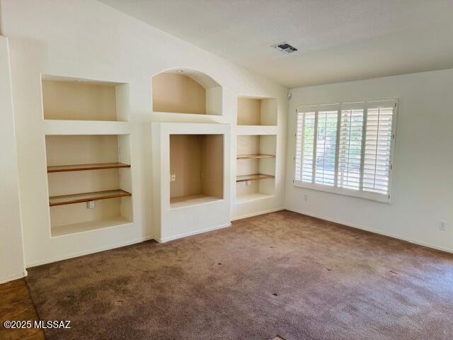 1370 N Birds Nest Rd, Green Valley, AZ 85614 - unfurnished living room featuring carpet flooring, baseboards, visible vents, and built in shelves