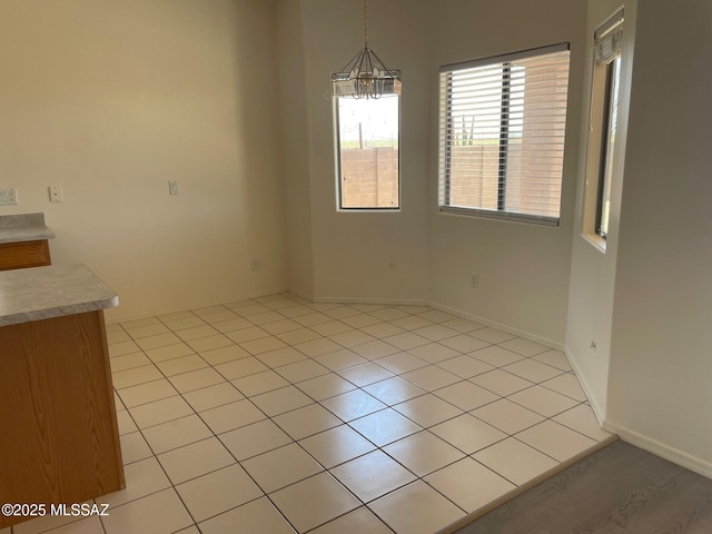 6610 S Via Molino De Viento, Tucson, AZ 85757 - unfurnished dining area featuring a chandelier, baseboards, and light tile patterned flooring