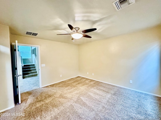 carpeted spare room with baseboards, visible vents, and a ceiling fan