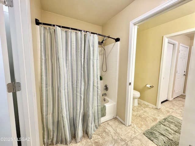 full bath featuring toilet, shower / bath combo, and baseboards