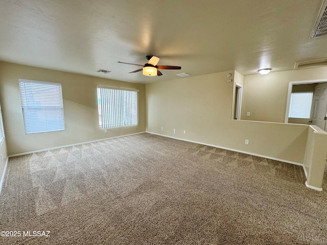 carpeted spare room featuring baseboards, visible vents, and ceiling fan
