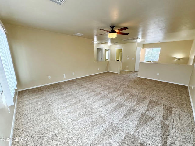 spare room with baseboards, visible vents, carpet, and a ceiling fan