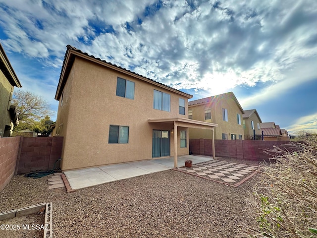 back of property with a fenced backyard, stucco siding, and a patio