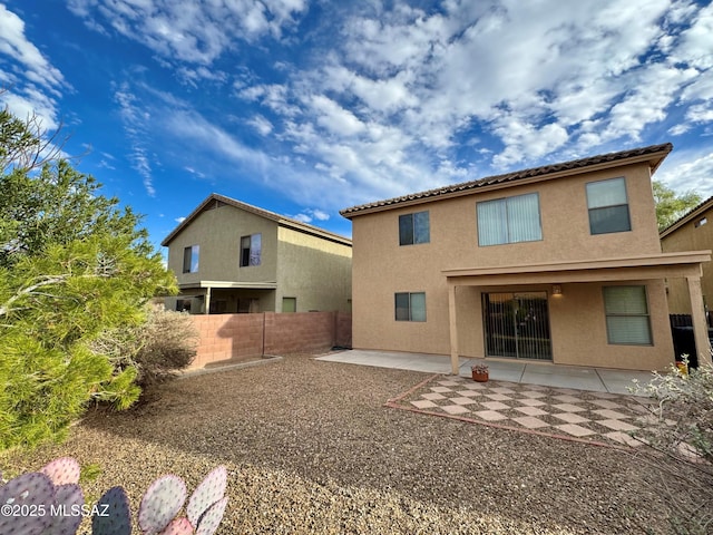 back of property featuring stucco siding, fence, and a patio