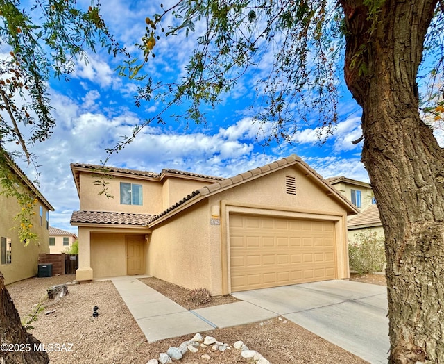 mediterranean / spanish home featuring driveway, a tile roof, cooling unit, stucco siding, and an attached garage