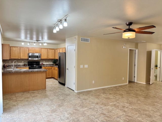 kitchen featuring open floor plan, dark countertops, a sink, and stainless steel appliances