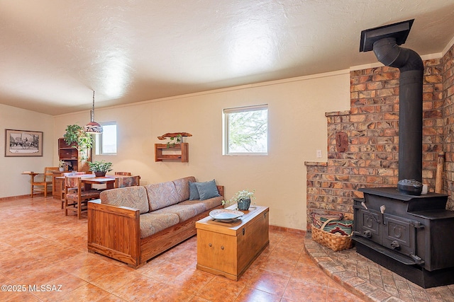 living area with a wealth of natural light, a textured ceiling, a wood stove, and light tile patterned floors