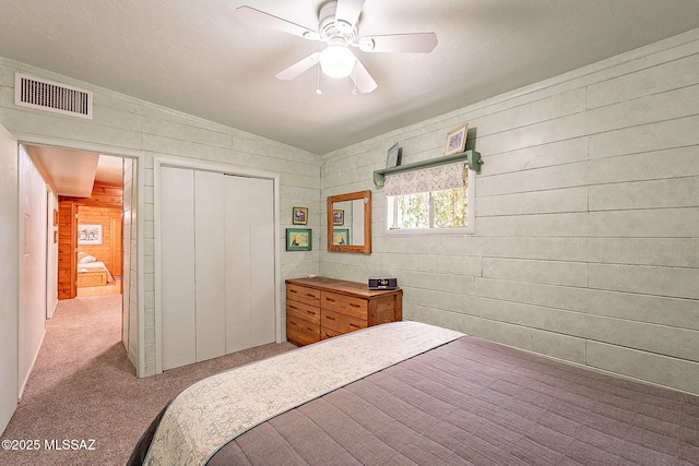 bedroom with a closet, ceiling fan, visible vents, and light colored carpet