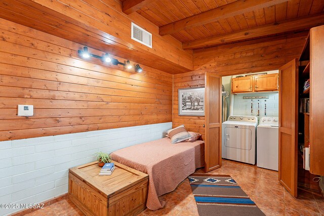 bedroom with wood walls, wooden ceiling, beam ceiling, visible vents, and washer and dryer