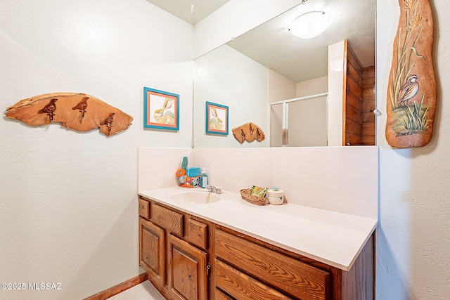 bathroom with baseboards, a stall shower, and vanity
